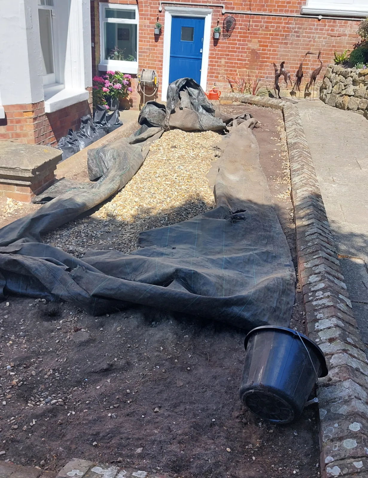 Barrier layer being laid beneath the garden shingle bed